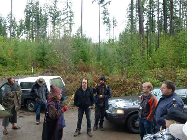Xwu'p'a'lich standing before loggers and RCMP asking for proof they have legal right to be on the land