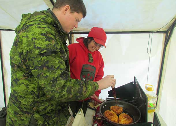 Corporal James Schmelzer learns how to make bannock under the watchful eye of Msaster Corporal Lucy Atlookan, a Canadian Ranger
