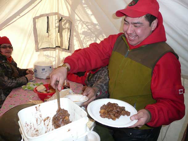 Ranger Howard Fiddler of Muskrat Dam helps himself to moose stew for lunch