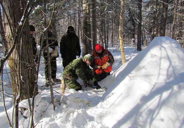 Sergeant Jean Rabbit-Waboose, a Canadian Ranger, right, teaches soldiers from the Lincoln and Welland Regiment, how to build a Quincy hut, an emergency snow house