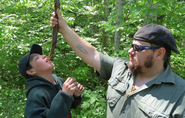 Junior Canadian Ranger Louis Wesley of Fort Albany drinks clean water from a wild grave vine held by outdoors expert Caleb Musgrave. Photo by Sgt. Peter Moon Canadian Rangers