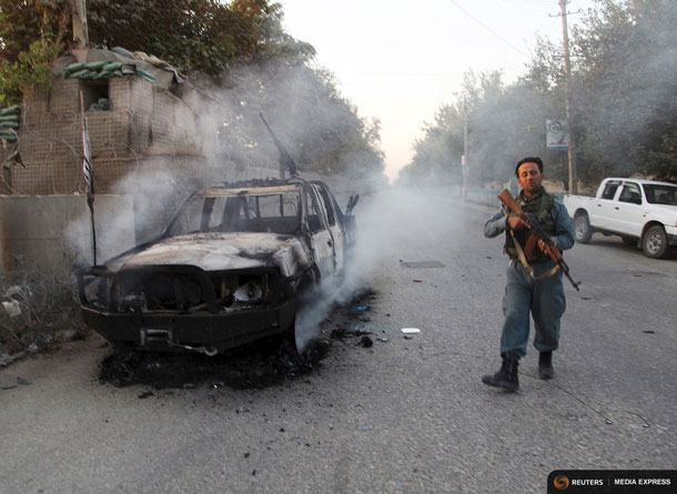 An Afghan policeman patrols next to a burning vehicle in the city of Kunduz, Afghanistan October 1, 2015.  REUTERS/Stringer
