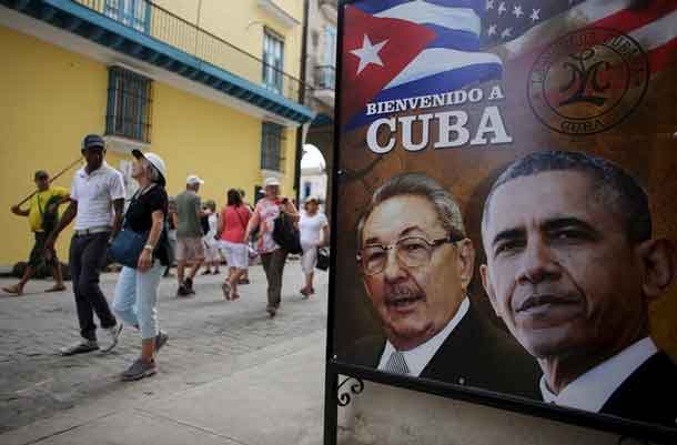 Tourists pass by images of U.S. President Barack Obama and Cuban President Raul Castro in a banner that reads "Welcome to Cuba" at the entrance of a restaurant in downtown Havana, March 17, 2016. REUTERS/Alexandre Meneghini