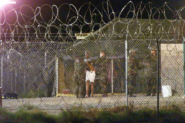 Marines at Camp X-Ray at the Naval Base at Guantanamo Bay, Cuba escort a newly arriving detainee into a processing tent after being showered in this February 7, 2002 file photo. REUTERS/Marc Serota/Files