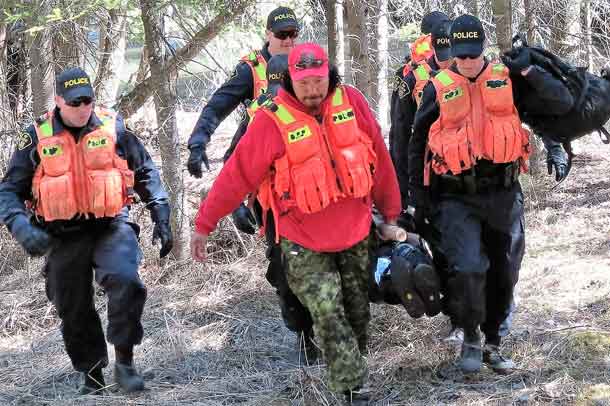 Master Corporal Isaac Barkman, centre, and OPP officers carry a "victim" out of the bush on an improvised stretcher
