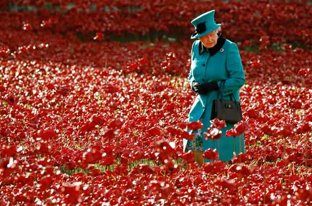 Queen Elizabeth walks through a field of ceramic poppies that form part of the art installation "Blood Swept Lands and Seas of Red", at the Tower of London in London October 16, 2014. REUTERS/Luke MacGregor