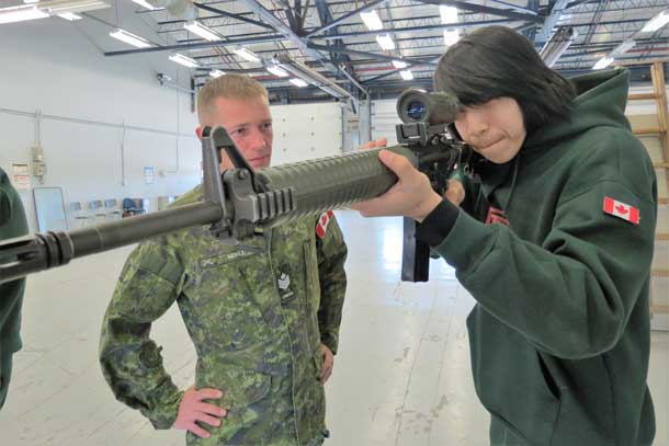 Junior Canadian Ranger Mason Sugarhead of Fort Hope training on the military C7 assault rifle under the watchful eye of an army instructor