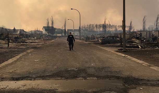 A Mountie surveys the damage on a street in Fort McMurray, Alberta, Canada in this May 4, 2016 image posted on social media. Courtesy Alberta RCMP/Handout via REUTERS