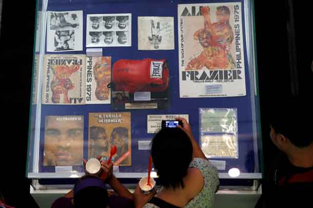 A fan uses a mobile phone to take pictures of late boxer Muhammad Ali's memorabilias of the 1970 bout with Joe Frazier, dubbed as "Thrilla in Manila" in Cubao Quezon City, Metro Manila, Philippines June 10, 2016.   REUTERS/Erik De Castro