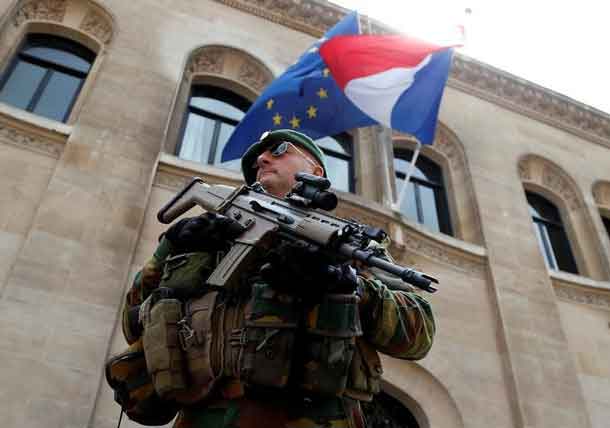 A Belgian soldier stands guard in front of the French embassy as French and European Union flags flutter at half staff to honor the victims of the Bastille Day truck attack in Nice, in Brussels, Belgium, July 15, 2016.  REUTERS/Francois Lenoir