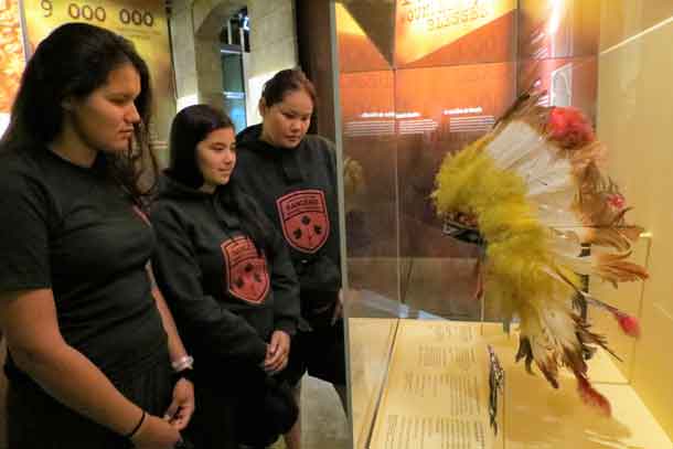 Junior Rangers Beth Baxter, Amber Lawson, and Laurinda Miles look at the ceremonial headdress and medals of Canada's most highly decorated indigenous soldier, Corporal Francis Pegahmagabow who won a Military Medal and two bars in the First World War.