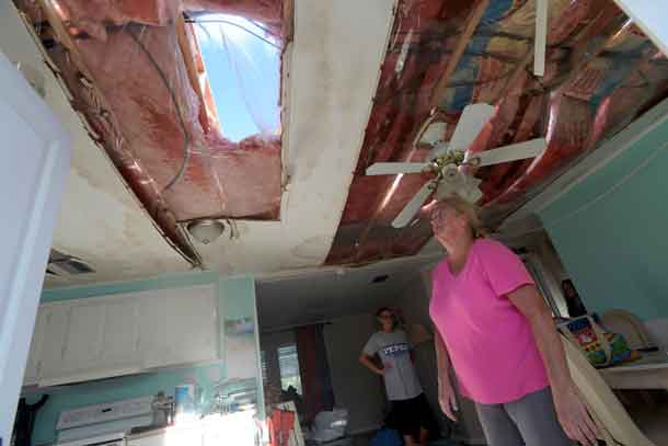 Diane Blumling (R) looks at a hole in the roof of her home while removing belongings in the aftermath of Hurricane Matthew at the Surfside Estates neighborhood in Beverly Beach, Florida, U.S., October 8, 2016.  REUTERS/Phelan Ebenhack