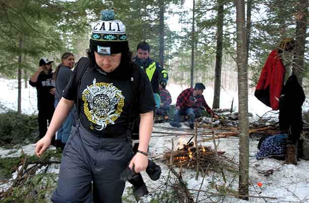 LEARNING TO SURVIVE in the winter on the land was provided to Wabun Youth during a week long youth gathering near Timmins. Pictured in the foreground is Max Worme, of Mattagami FN heading to get wood for the fire. 