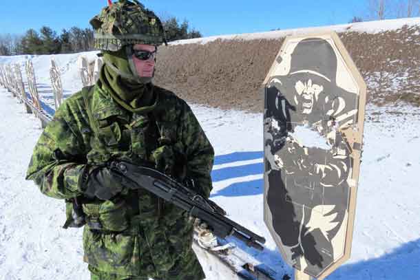 Warrant Officer Ron Wen examines the extensive damage a shotgun does to a target on a shooting range at CFB Borden.