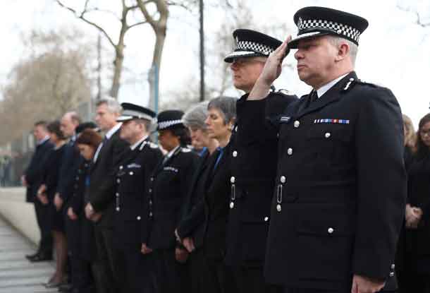 Police officers salute during a minute's silence outside New Scotland Yard. REUTERS/Neil Hall