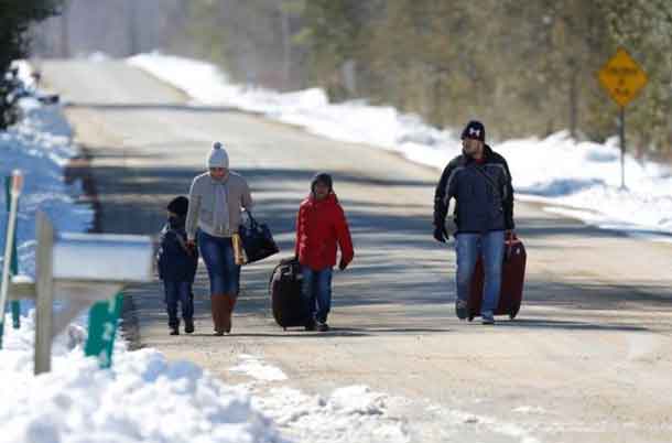 A family that says they are from Colombia walks down Roxham Road toward the U.S.-Canada border leading into Hemmingford, Quebec, Canada March 26, 2017. The family crossed the border and were arrested by waiting Royal Canadian Mounted Police (RCMP) officers. REUTERS/Christinne Muschi