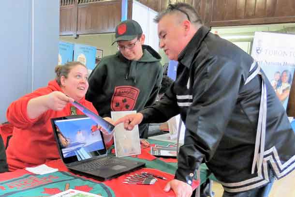 Corporal Kayla Blakney and Junior Canadian Ranger Jordan Macklin show Elder Stephen Paquette a Canadian Ranger publication at Toronto indigenous careers fair.