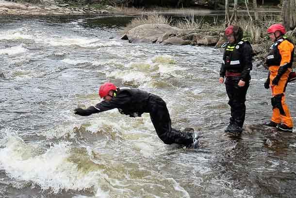 An army instructor dives into fast moving water during rescue training.