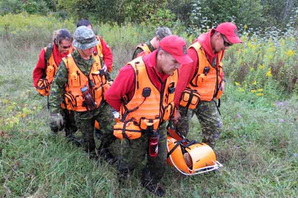Canadian Rangers use a stretcher to carry a victim out of the bush during search and rescue training.