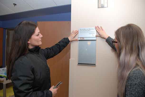 Fiona and Hope Duncan place a plaque outside a patient room in Unit 1A at the Hospital in commemoration of the significant contributions of the Dave Duncan Memorial Golf Tournament to the Northern Cancer Fund.