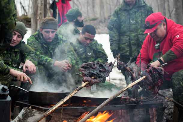 Sergeant Matthew Gull, right, shows soldiers from the Toronto Scottish Regiment how to cook geese over an outdoor fire.