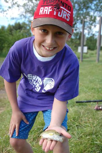 Camper Denver showing off one of the five fish he caught today in the fishing pond at KOA Campground.