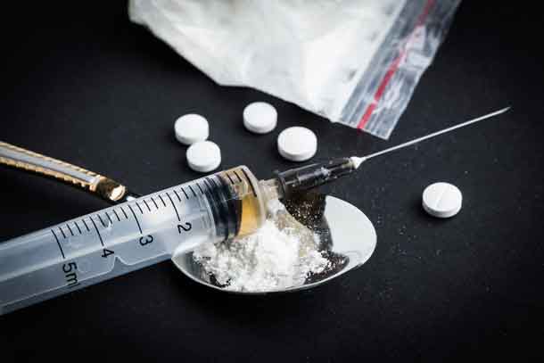 Detox from heroin - Drug syringe and cooked heroin on spoon Image Depositphotos.com