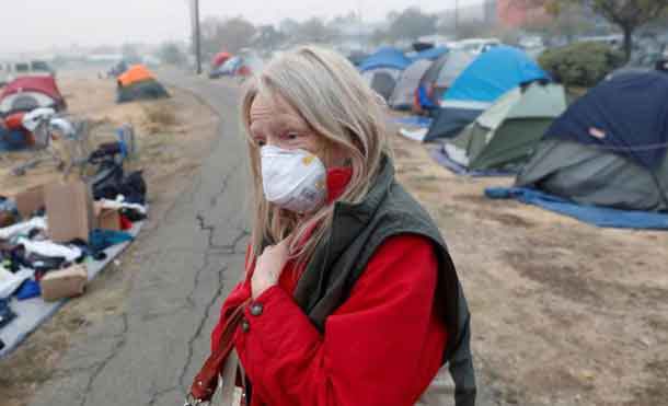 Bridgett Hogan, 57, of Paradise, walks through a makeshift evacuation center for people displaced by the Camp Fire in Chico, California, U.S., November 15, 2018. REUTERS/Terray Sylvester