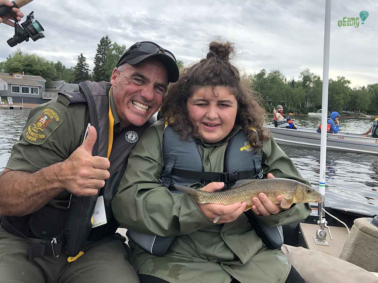 Camper Danica shows off the fish she caught with Conservation Officer Keith