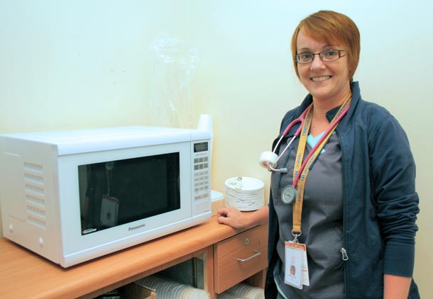 Emergency Department nurse Melanie Banfield with the D-Side Kitchen’s new microwave. Patients and family members can use it to heat up coffee, soup, and other items to make their wait more comfortable.
