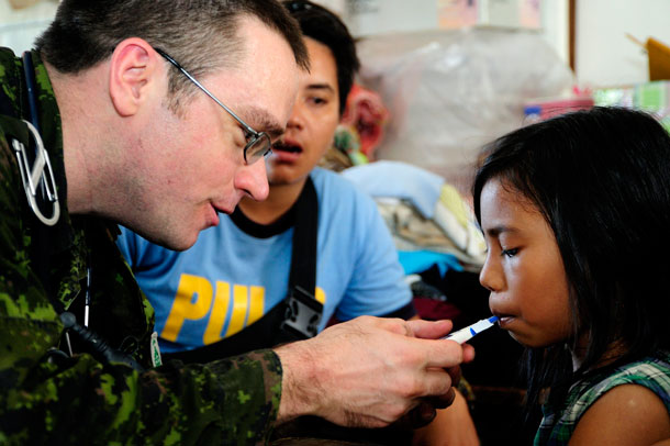 Captain Ian Schoonbaert, a Doctor from the Disaster Assistance Response Team (DART) checks a local Philippian child in a refuge camp out side of Roxas city on November 16, 2013 after the area was devastated by Typhoon Hailan, one of the largest typhoons on record. Corporal Darcy Lefebvre, Canadian Forces Combat Camera Photographer