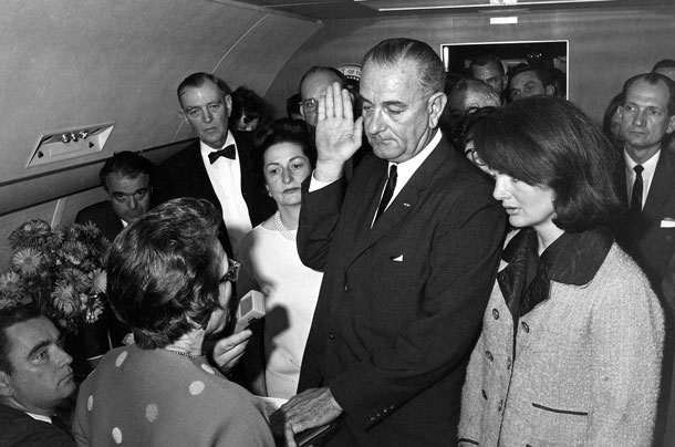 Aboard Air Force One, President Johnson is sworn in - Mrs. Kennedy in her still blood stained suit by his side. Photo John F. Kennedy Presidential Library.