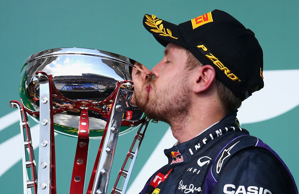 Standing atop the podium Sebastian Vettel celebrates with the trophy