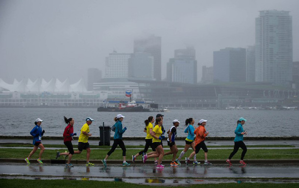 Running enthusiasts sprinted along the Stanley Park Seawall, across from downtown Vancouver's Coal Harbour area, at the 2014 BMO Vancouver Marathon on Sunday, May 4, 2014. Over 13,000 participants overcame a downpour to finish Canada's premier West Coast marathon. (Darryl Dyck/The Canadian Press Images/BMO Financial Group)