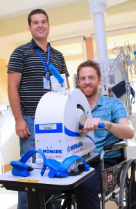 Student Mike Twigg (right) demonstrates how patients can use the new arm ergometer, purchased with a Family CARE Grant, to get much needed exercise as Mike Paularinne, Advanced Practice Physiotherapist in the ICU looks on.