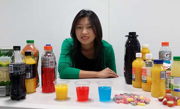 University of Adelaide School of Dentistry Honors student Chelsea Mann with a selection of acidic drinks and sweets that can cause permanent damage to teeth.