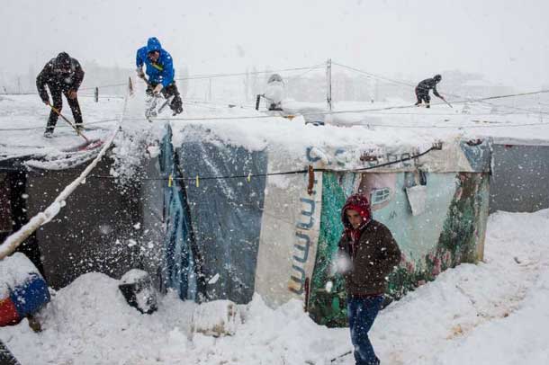 Syrian refugees remove snow from their shelters at an informal tented settlement in the Bekaa Valley, Lebanon, during a blizzard. Photo: UNHCR/A. McConnell