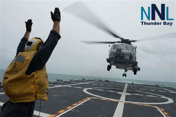 U.S. Navy Petty Officer 2nd Class Adam Garnett signals an MH-60R Sea Hawk helicopter from Helicopter Maritime Strike Squadron 35 on the flight deck of the littoral combat ship USS Fort Worth, Jan. 3, 2015. Fort Worth is currently in the Java Sea conducting helicopter search-and-recovery operations with the USS Sampson as part of Indonesian-led efforts to locate downed AirAsia Flight 8501. U.S. Navy photo by Petty Officer 2nd Class Antonio P. Turretto Ramos