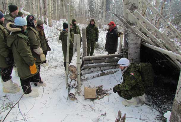 Canadian Ranger Master Corporal Joe Lazarus, standing right, shows soldiers how to build as emergency shelter