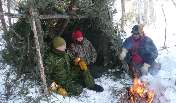Brigadier-General David Patterson tries out an improvised shelter built by two Canadian Rangers