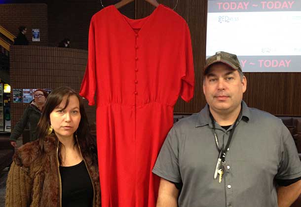 Artist Jaime Black (left) and Student Union President Chris Cartwright stand by one of over 100 red dresses displayed on campus this week.