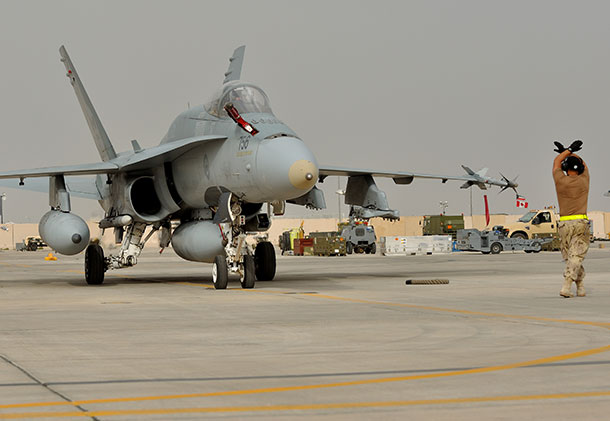 An Air Task Force-Iraq (ATF-I) technician guides the pilot of a CF-188 Hornet fighter jet onto the ramp after the first Canadian airstrike over Syria during Operation IMPACT on April 8, 2015. Photo: Op Impact, DND