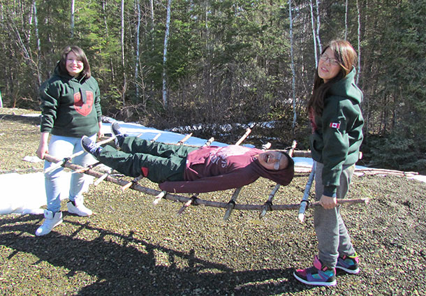 Trying out an improvised stretcher they built are, from left, Lac Seul Junior Canadian Rangers Maleena Ledger, Justice Brisket, and Maleyah Ledger.