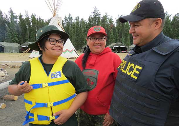 ior Canadian Ranger Autumn Sutherland of Fort Albany tries on one of the life jackets donated by OPP Sergeant Marty Singleton, while Ranger Jessie Sutherland, centre, looks on.