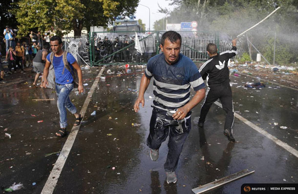 Migrants run as Hungarian riot police fires tear gas and water cannon at the border crossing with Serbia in Roszke, Hungary September 16, 2015. Hungarian police fired tear gas and water cannon at protesting migrants demanding they be allowed to enter from Serbia on Wednesday on the second day of a border crackdown. REUTERS/Marko Djurica TPX IMAGES OF THE DAY