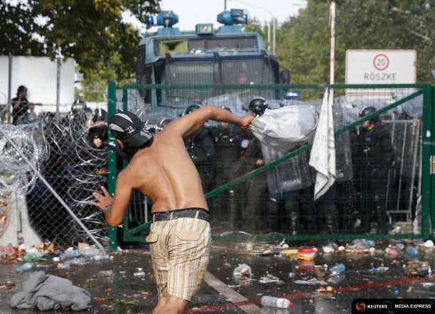 Migrants react on the Serbian side of the border as Hungarian riot police fires tear gas and water cannon near Roszke, Hungary September 16, 2015. REUTERS/Marko Djurica