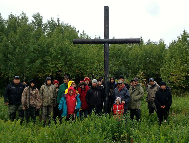 Elders, adults and youth stop at the old settlement of Winisk to say a prayer at the old cemetery before continuing home.
