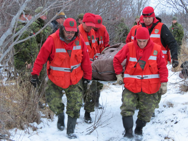 Canadian Rangers carry a drug overdose "victim" out of the bush after finding him during a search and rescue exercise in Sachigo Lake