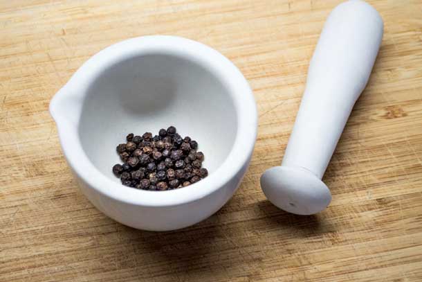 Black peppercorns with pestle and mortar. Credit iStock Christopher Stokey