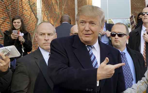 U.S. Republican presidential candidate Donald Trump points at a supporter at a polling place for the presidential primary in Manchester, New Hampshire February 9, 2016. REUTERS/Rick Wilking .